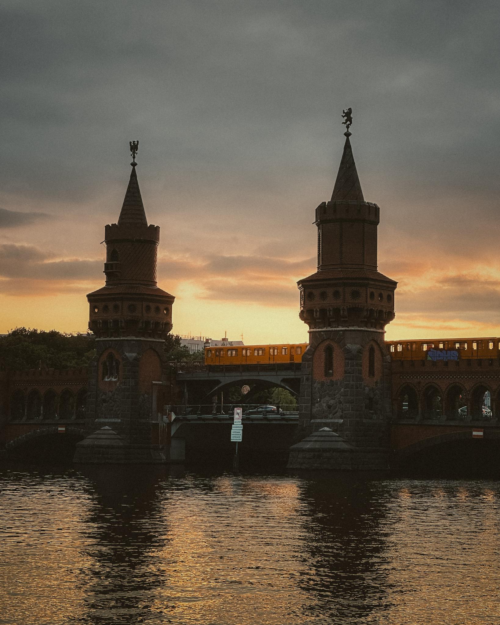 Scenic view of the historic Oberbaum Bridge in Berlin during sunset, with reflection on the river.